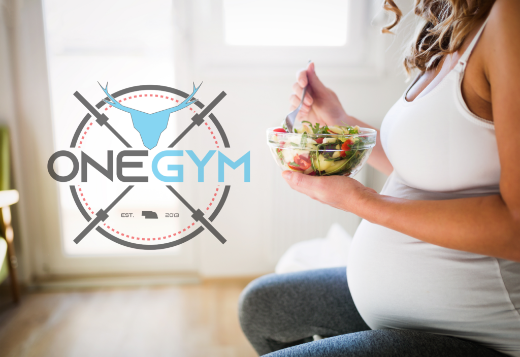 Happy expectant mother enjoying a balanced meal with fruits, vegetables, and lean protein, emphasizing the importance of nutritious eating during pregnancy.